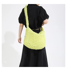 Detail of light green pleated bubble texture shoulder bag worn by model over black outfit