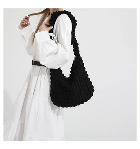 Detail of black pleated hobo bag showing high-density bubble texture and wide shoulder strap