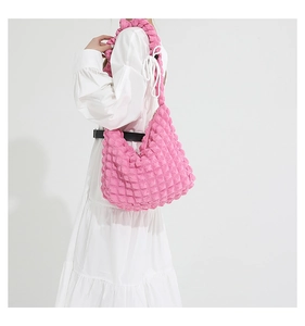 Pink bubble textured shoulder bag with white ribbon detail worn by model in a side view