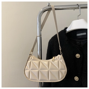 Dettaglio della borsa baguette trapuntata beige con cuciture geometriche e zip dorata