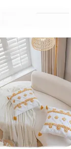 Close-up of tufted geometric texture and corner tassels on a creamy white Nordic pillow