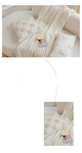 Detail view of cream tufted pillow with clover pattern and matching knit throw blanket