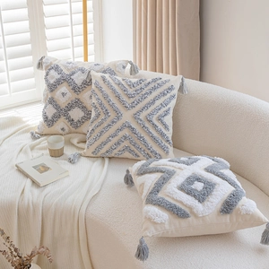 Nordic tufted geometric throw pillow with grey tassels on a minimalist cozy sofa