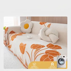 Chenille sofa cover with orange tulips and tassel edges on a minimalist cream background