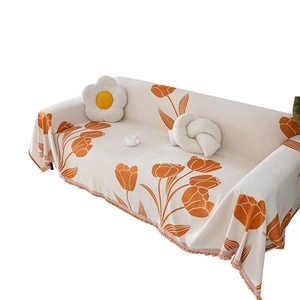 Chenille tulip sofa cover with orange floral print and tassels on a cream fabric