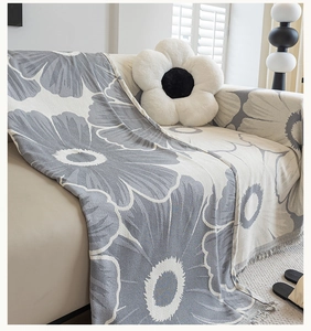 Close-up of grey and white daisy chenille sofa cover featuring soft fringe and floral weave