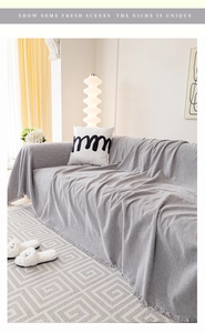 Close-up of gray chenille sofa cover with decorative fringe in a cozy living room