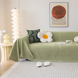 Light green chenille sofa cover with fringed edges in a minimalist living room setting