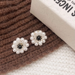 Detail of vintage flower stud earrings with miniature pearls and black center bead