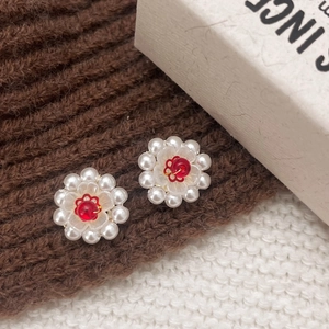 Retro handmade daisy earrings with white pearls and red gemstones on knit fabric