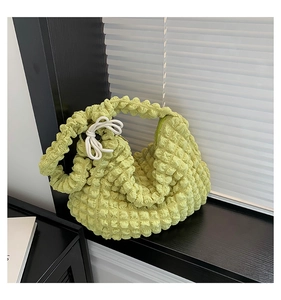 Detail of light green popcorn texture fabric handbag with side white ribbon bow detail