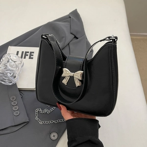 Minimalist black hobo shoulder bag with a silver metal bow accent and chain strap