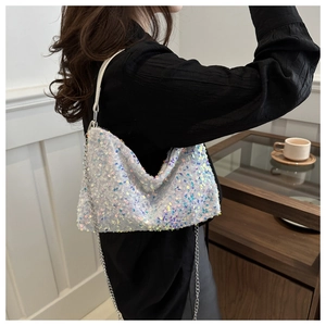 Detail of iridescent sequin shoulder bag with metal chain strap on model in black top