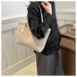 Detailed view of beige woven tote bag with white leather straps and reinforced rivets