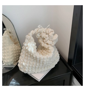Detail of white pleated cloud bag with popcorn texture on a minimalist stand