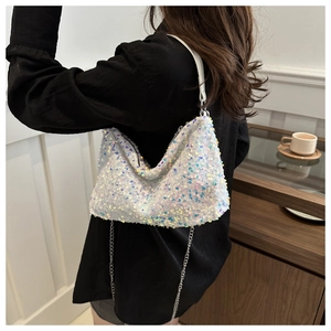 Close-up of a white iridescent sequin shoulder bag with a silver chain strap on a model