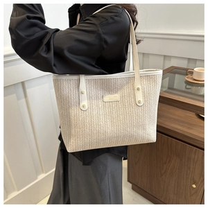Detail of the woven texture and leather handle on this off-white large straw tote bag