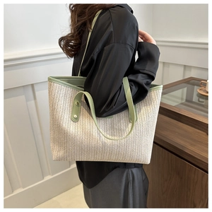 Detail of ivory woven tote bag with green leather trim showing side capacity on model