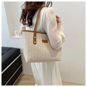 Detail of handwoven cream tote bag with brown leather handles and brand leather patch