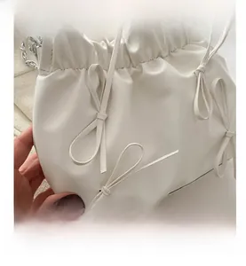 Détail du sac seau plissé blanc orné de trois nœuds et d'une bandoulière chaîne