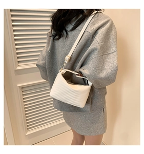Détail du sac bandoulière blanc à motifs verticaux et accessoires en métal doré