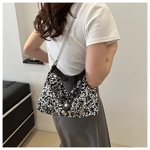 Close-up of elegant black sequin shoulder bag with silver chain strap worn by a model