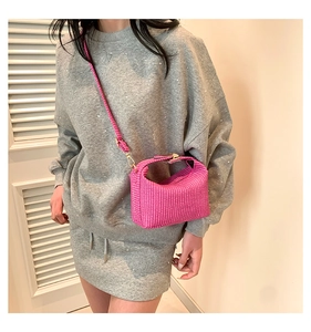 Détail d'un sac bandoulière tissé rose vif avec des ferrures dorées et une texture riche
