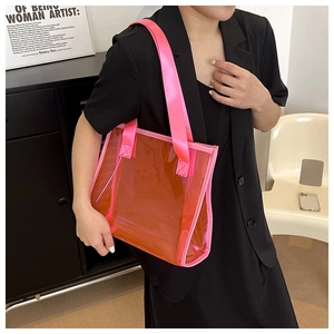 Detail of orange transparent PVC tote bag with pink straps worn by a model