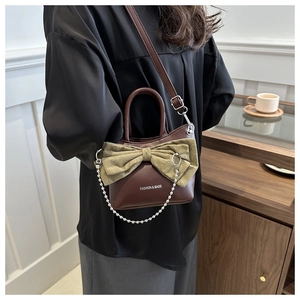 Détail du sac bandoulière avec nœud vert, chaîne perlée et bandoulière sur un mannequin
