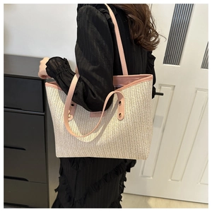 Detail of herringbone straw tote bag with pink leather trim and handle reinforcement