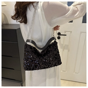 Detail shot of black sequin shoulder bag with silver chain strap on white outfit