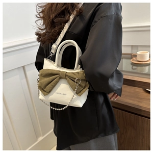 Photo de style de vie d'un sac bandoulière en cuir blanc orné d'un grand nœud vert olive