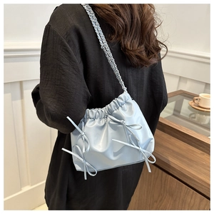 Détail du sac seau plissé bleu clair avec nœuds et bandoulière chaîne argentée