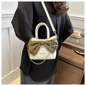 Detail of white PU leather handbag with green suede bow and silver chain strap