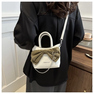 Detail of white PU leather bucket bag featuring a large olive green bow and silver bead chain