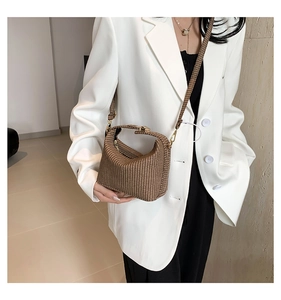 Braune Handtasche mit Webstruktur und Goldbeschlägen am Model mit weißem Blazer