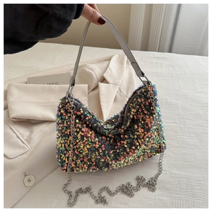 Close-up of sparkling sequin surface with metallic chain strap and zipper closure details