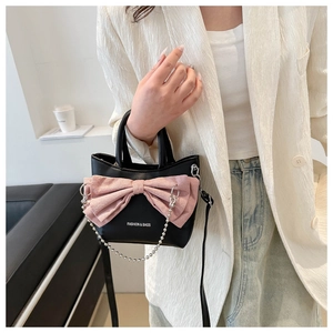 Close-up of black mini tote bag featuring a large pink bow and silver bead chain detail