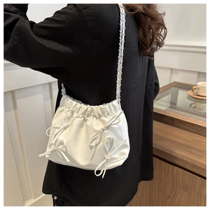 Détail du sac seau blanc plissé avec nœuds élégants et bandoulière en chaîne argent