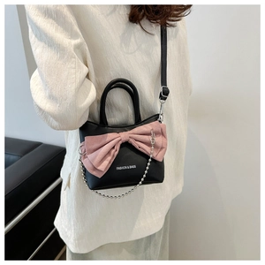 Detail shot of black handbag with pink bow, silver chain, and fashion lettering decoration