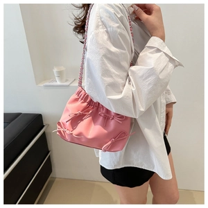 Détail du sac seau rose à nœuds avec bandoulière chaîne et texture en cuir PU plissé