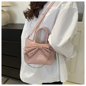 Détail du sac bandoulière rose avec grand nœud et bandoulière en perles argentées