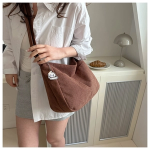 Detail of brown corduroy hobo tote bag texture and cute puppy charm on shoulder strap