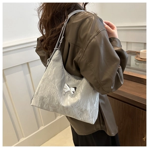 Detailed close-up of a silver crescent shoulder bag featuring a metallic butterfly buckle