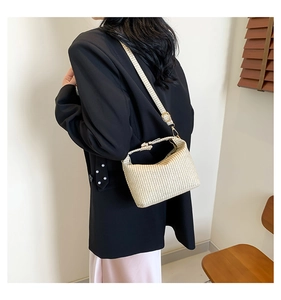 Détail du sac bandoulière en paille tissée beige avec texture et boucle en métal doré