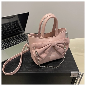 Pink shoulder bag detail with matte bow decoration and metallic pearl chain strap