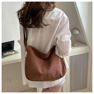 Detail of dark brown corduroy shoulder bag with adjustable strap and cartoon pendant