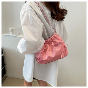 Détail du sac seau plissé rose avec nœuds décoratifs et bandoulière chaînette
