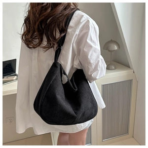 Detail of black corduroy tote bag showing thick ribbed texture and silver charm