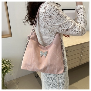 Close-up of pink pleated tote bag with silver butterfly emblem and metal chain strap